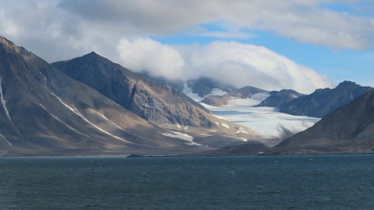 Foto des Hornsund mit dem Gletscher Gasbreen, Spitzbergen, Norwegen, im Hintergrund und Wolken über den Bergen.