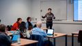 The picture shows workshop participants while Edison Blakcori stands in front of a whiteboard and explains something.